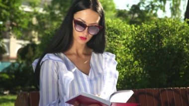 Güneş gözlüğü ve soyulmuş bluz şık kadın yaz park kitap okumak
