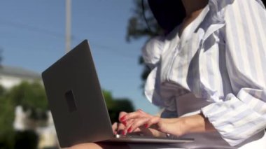 Şık kadın parkta dizüstü bilgisayarda yazarak