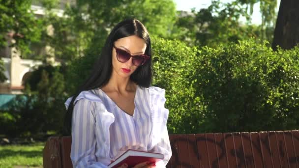 Beautiful woman finished reading book and close it, summer park — Stock Video