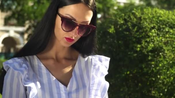 Портрет стильної жінки в сонцезахисних окулярах парку — стокове відео
