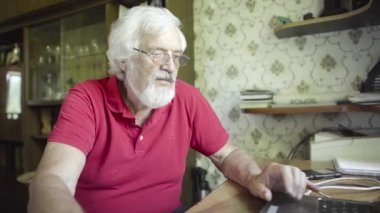 Evde dizüstü bilgisayar kullanan kıdemli adam.