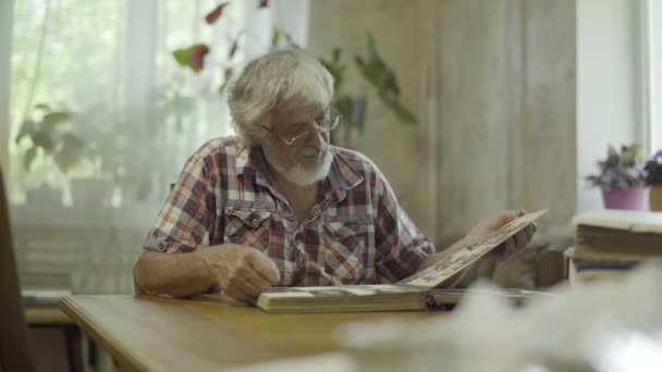 Зрелый мужчина смотрит на свои старые фотографии из молодости — стоковое видео