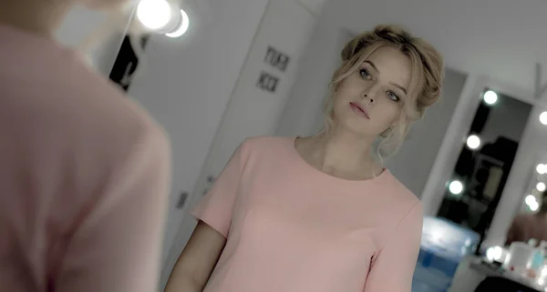 Sensuell ung jente med profesjonell sminke, i rosa kjole, se på speilet – stockfoto