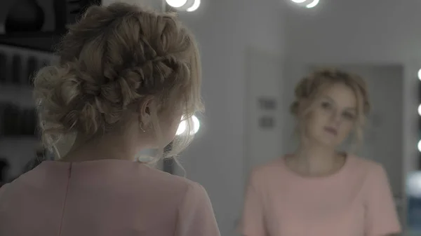 Vakker jente med profesjonell frisyre, sminke ser på speil i studio – stockfoto