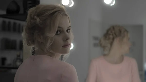 可爱的年轻女孩在粉红色的礼服看相机反射镜中的背景 — 图库照片