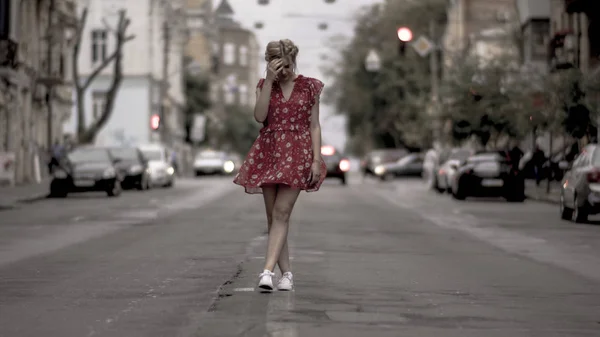 Kaunis tyttö punainen mekko poseeraa kameran kaupunkien tiellä autoja tekijänoikeusvapaita kuvapankkikuvia