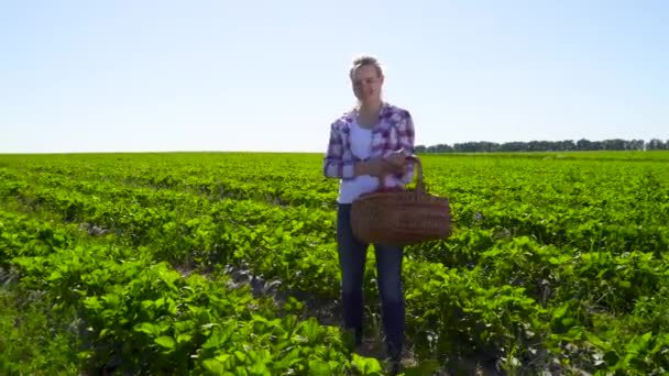 Gelukkig meisje houdt mand vol aardbeien bij groene plantage achtergrond — Stockvideo