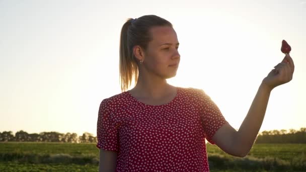 Chica joven con fresa en el fondo del atardecer — Vídeo de stock