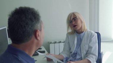 Yetişkin adamla doktorlar resepsiyonda konuşan doktor