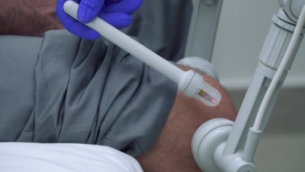 Rehabilitólogo examinar la rodilla del hombre adulto con equipo especial — Vídeo de stock