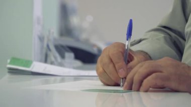 Resepsiyon yakın klinik ayakta formu doldururken komuta sizde. Olgun adam hastane ziyaret edin. Yakın çekim.