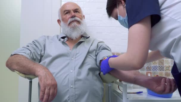 Доктор готовит пожилого человека к взятию крови из вены — стоковое видео