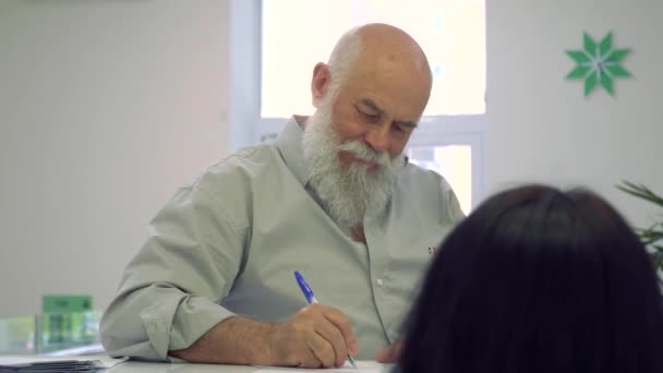 Starší muž fiil formuláři v nemocnici na recepci — Stock video