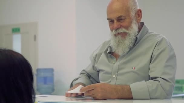 Homem idoso conversando com recepcionista no hospital — Vídeo de Stock