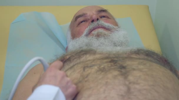 Doctor examining abdomen of senior man with ultrasonography equipment — Stock Video