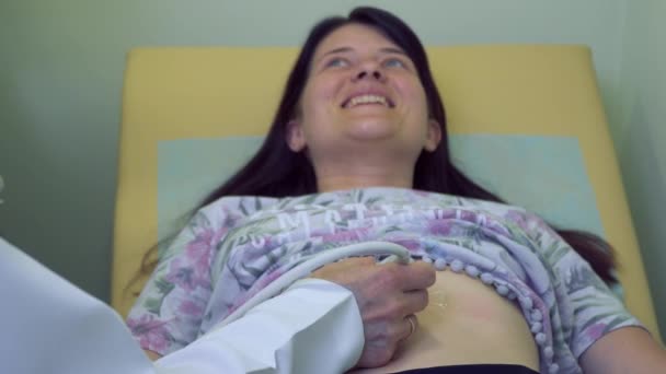 Врач проверяет брюшную полость женщины с помощью ультразвукового оборудования — стоковое видео