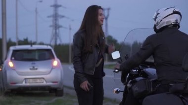 Genç güzel kız ona kırık bir araba ile yardım için birini yakalamak deneyin. Motorcu durur ve kız yakın ne olduğunu sor. Kadın, arka plan, kırık arabası ile bir yardım isteyin.