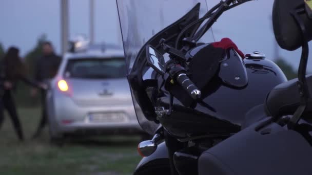 Люди разговаривают возле машины на размытом фоне мотоцикла — стоковое видео