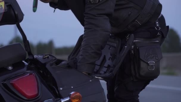 Байкер берет инструменты из багажника мотоцикла — стоковое видео