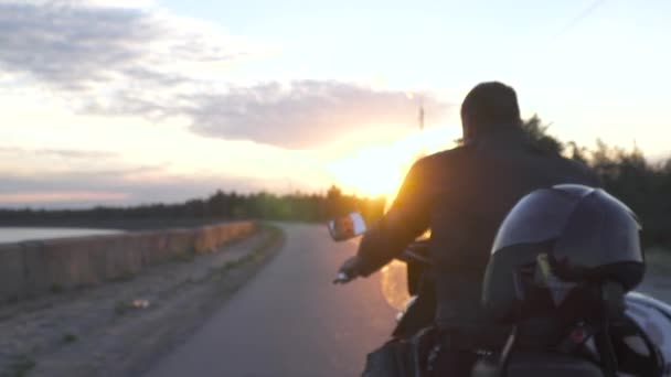 Fietser op motorrijden op de weg bij zonsondergang achtergrond — Stockvideo