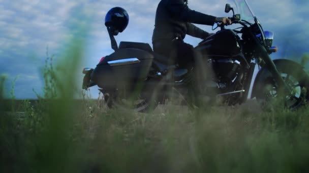 Un motard s'arrête sur la route et prend un instrument d'un coffre de sa moto — Video