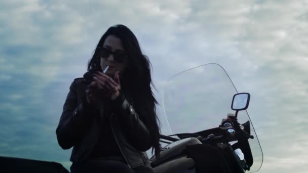 Девушка-байкер курит сидя на мотоцикле — стоковое видео