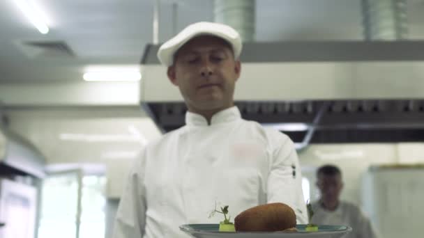 Шеф-кухар тримає готову страву на тарілці на кухні ресторану — стокове відео
