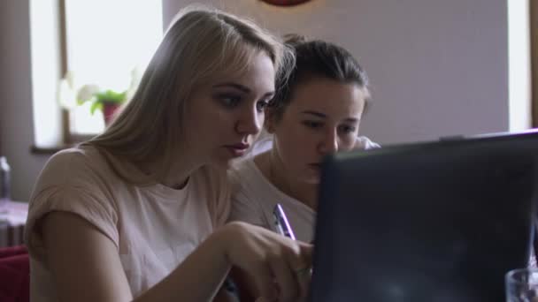 Две девушки обсуждают использование ноутбука — стоковое видео