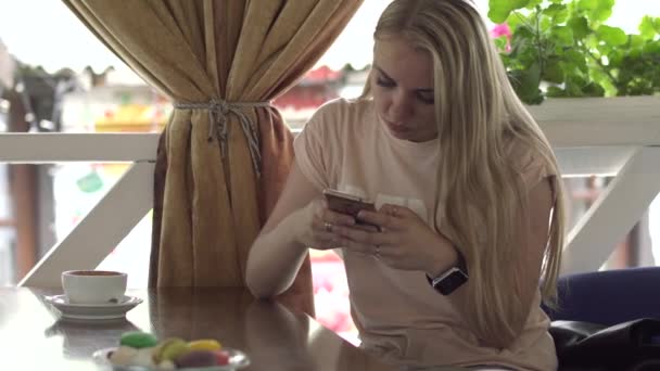 Dos mujeres jóvenes mirando en la pantalla de teléfonos móviles en la cafetería — Vídeo de stock