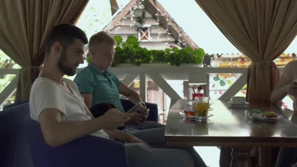 Twee jonge man met behulp van telefoons in café — Stockvideo