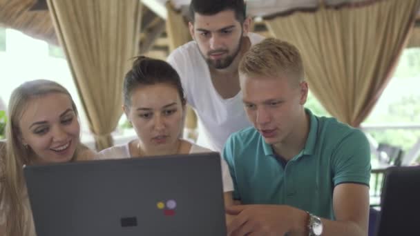 Gesellschaft von Freunden schaut auf den Bildschirm des Laptops im Café — Stockvideo