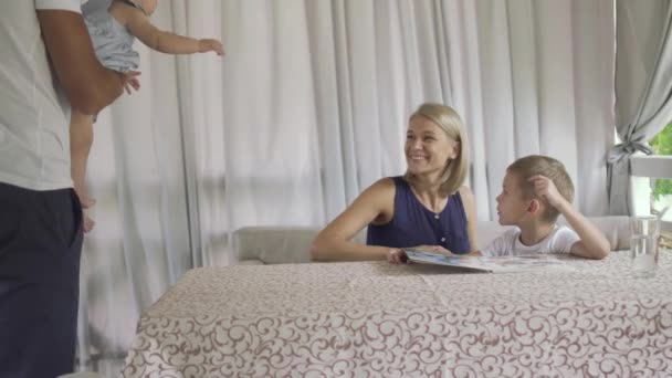L'homme donne une petite fille à une mère dans un café assis à table avec son fils — Video