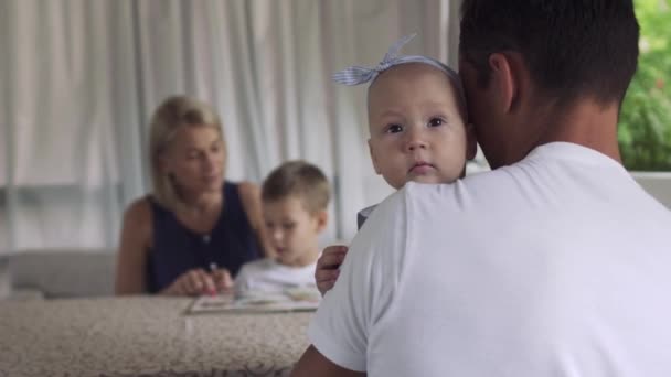 Padre sostiene hija bebé, niña mira a la cámara — Vídeos de Stock