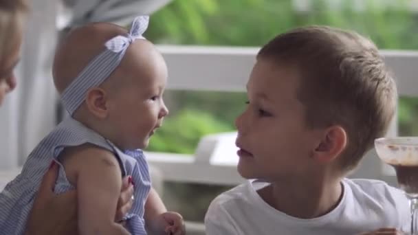 Petit garçon s'amuse avec sa petite sœur et mange de la glace dans un café — Video