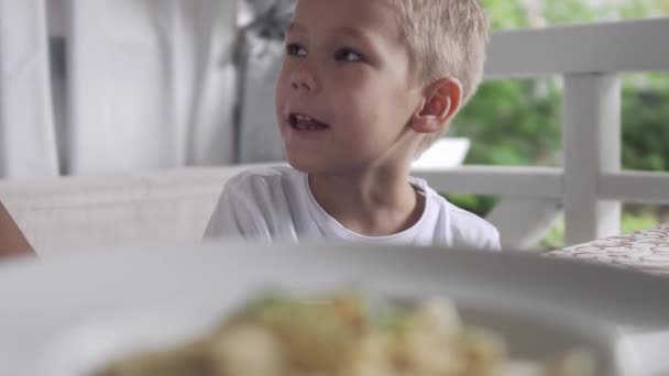 Тарілка з пельменями на столі, маленький хлопчик позаду — стокове відео