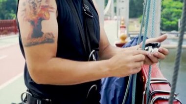 Genç adam bir ip bir karabina bir köprüde bağlar.