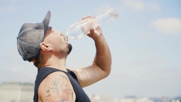 Mann mit Mütze und Tätowierung trinkt Wasser — Stockvideo