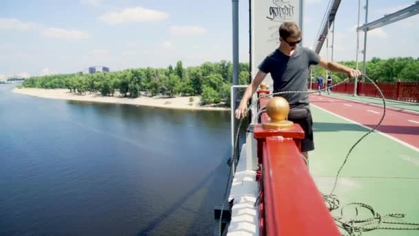 Guy pomalu snižuje lano z mostu — Stock video