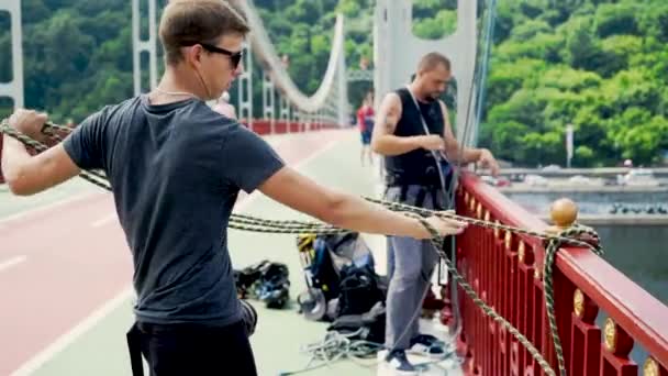 Młodzi ludzie zawiązać ubezpieczenia do skoków na moście. — Wideo stockowe