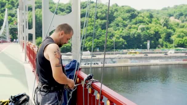 Jonge man zorgt voor de verzekering voor het springen vanaf de brug — Stockvideo