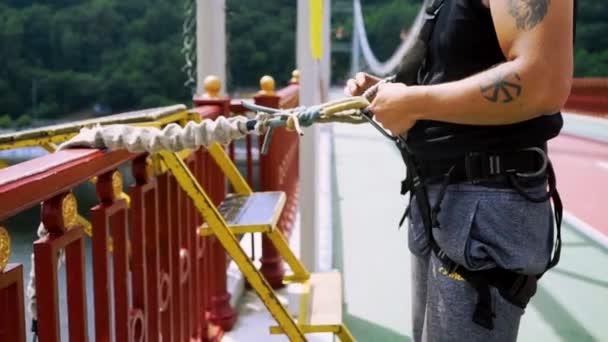 Парень прикрепляет к себе страховочную веревку для прыжков — стоковое видео