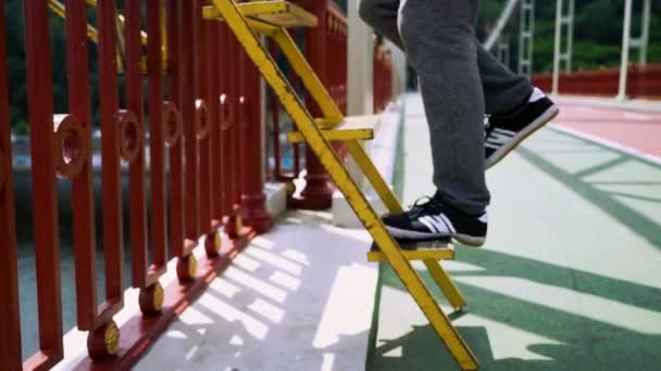 Chlap vyleze po schodech k okraji mostu — Stock video