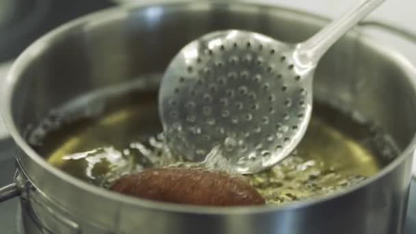 Повар берет котлет из кипящего масла с лопаткой в замедленной съемке — стоковое видео
