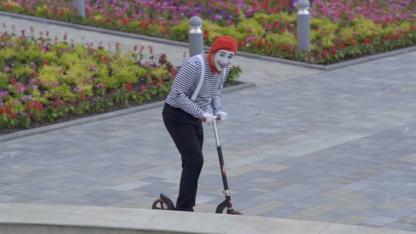 Rolig mime i röd basker ridning på en kick scooter — Stockvideo