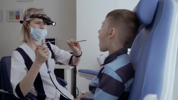 Arzt untersucht Kehle von kleinem Jungen mit Fernrohr — Stockvideo