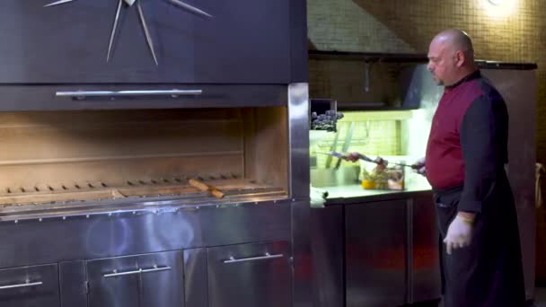 Masakan dari restoran uzbek menaruh daging mentah pada tusuk sate pada panggangan di dapur — Stok Video