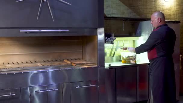 Cocinero del restaurante uzbek sosteniendo un pincho con carne cruda y mirando a la cámara — Vídeo de stock