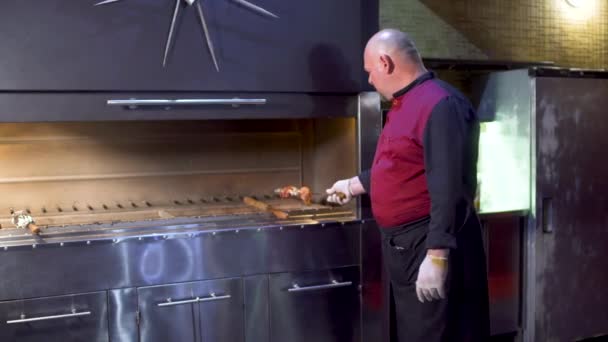 Cocinar en uniforme poner pincho con carne cruda en la parrilla en la cocina del restaurante — Vídeos de Stock