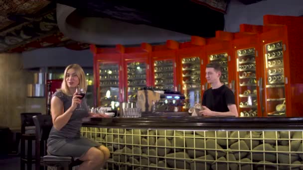 Beautiful adult woman drinks wine near bar counter in restaurant — Stock Video