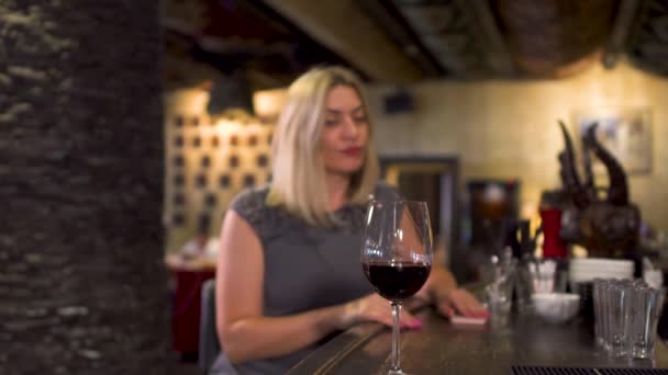 La mujer está nerviosa esperando a alguien y bebe vino en el restaurante — Vídeo de stock